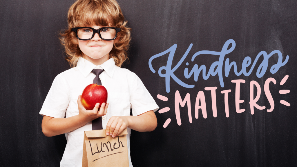 Young boy holding an apple and sack lunch with text that reads "Kindness Matters".